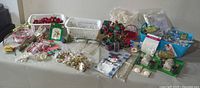 Wide view of table displaying the assortment of holiday and Christmas crafting materials with various containers and packages.