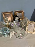 Full overview of all lot contents displayed on a table including mirrors, clock, picture frame, vases, candle holders, ceramic unicorn shaker, and ashtray