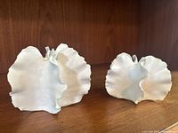 Two white ceramic pottery pieces on a wooden surface, showing their size and form.