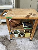 Top view showing stains and wear on the wooden surface plus part of the handle and wheels