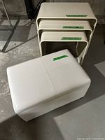 Photo showing three white MCM metal nesting tables and white vinyl stool/chest with measurement tape on each item