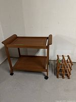 Full view of teak bar cart and bottle holder in basement setting