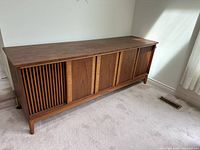 Front view of the Telefunken console stereo showing vertical slatted wooden panels and solid wooden center panels with visible small chip on the edge.