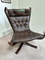 Front angle view of brown leather lounge chair with tufted seat and back