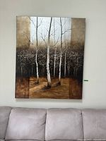 Frontal view of the large forest painting showing birch trees with gold and brown tones, hanging on a white wall above a couch.