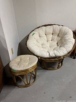 Papasan chair and matching stool next to wall on concrete floor showing frame and cushion condition.