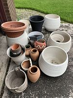 Overview showing large white ribbed planters, terracotta and ceramic pots, black resin planter, and basket-style planter