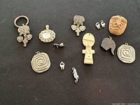 Photo showing assorted pendants and charms arranged on black background.