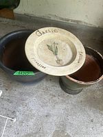 Ceramic garlic plate on top of two terracotta and ceramic pots, visible wear and dirt