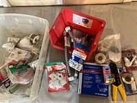 Wide-angle photo showing assorted plumbing parts including toilet seat boots, gasket, plumbing tools, and connectors in bins and original packaging.