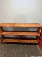 Front view of the solid wood vintage bookcase showing three open shelves and the base with tapered legs.