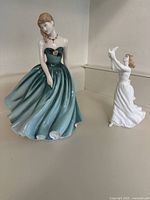 Photo showing both Royal Doulton figurines, Sarah in green dress and Thinking of You with white dress and bird.