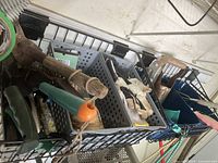 Plastic baskets with gardening gloves, string, and long-handled tools like bulb planters and shovels.