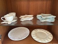 Two Blue Sky cream starfish teacups with saucers, 6 starfish-shaped plates in cream and turquoise, 2 large round plates with starfish design, and 1 large white ceramic starfish plate.