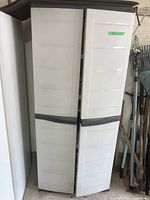 Closed view of the plastic resin storage cabinet showing the front doors with black door handles and off-white color.