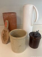 Photo showing all five items: Thermos carafe, clay wine cooler, beige crock, brown sugar crock with lid, and wooden fish mold.