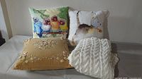 Lot showing three throw pillows and the white knit afghan together on a flat surface.