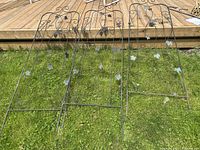 Full view of all three metal garden trellises showing their size and design against a grass background with wooden deck behind.