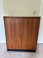 Front view of closed cabinet showing wood veneer doors and black base