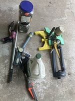 Overview of various sprinklers, hose nozzles and watering accessories arranged on a concrete floor.
