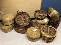 Several wicker pieces including baskets, planters, and bread baskets arranged together. Shows variety of shapes and weaves.