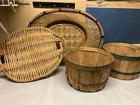 Photo showing two oval wicker trays and two small wooden bushel baskets with green metal bands.