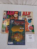 Three comics: two Alf comics with Marvel branding and one Adventure Time comic issue #17, all laid out on a bed.