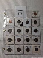 Array of Canadian nickels and penny coins in individual holders arranged in plastic binder pages, labeled by year and condition.
