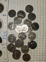 Close-up photo of Canadian coins scattered on fabric surface showing detail of coin designs and condition.