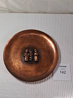 Top view showing the full copper plate with hammered finish and central decorative relief of three figures.