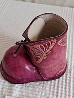 Side view showing purple leather boot with embossed butterfly details and front lace.
