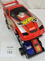 Red Hot Wheels carrier car with sliding drawer extended, showing two small toy cars inside