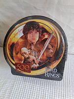 Front view of the Lord of the Rings puzzle metal tin showing main character artwork and 500 pieces label
