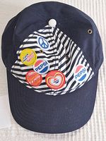 Front view of navy blue Pepsi baseball cap with six retro pins on striped front panel.