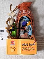 Front view of the PEZ candy dispenser showing Wile E. Coyote with slingshot and Road Runner inside the oven dispenser mechanism.