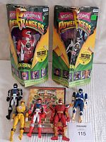 Photo showing two large Power Rangers figures in original boxes with visible wear and five smaller figures in front along with Power Rangers Samurai DVD.