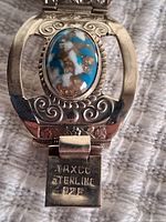 Close-up of clasp side of sterling silver bracelet showing 'TAXCO STERLING 925' stamp and turquoise stone detail.