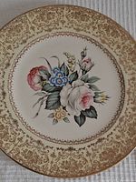 Front view of a decorative plate with floral Tudor Rose design and 23K gold filigree border.