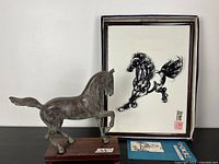 Vintage bronze horse statue mounted on wooden base next to framed horse artwork with Asian script stamps
