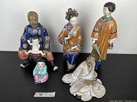 Five Chinese decorative painted porcelain figurines on a black surface against white background, showing full figures and colors.