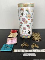 Overview of porcelain stand, silk pouches and brass hangers on table with scale