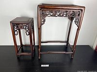 Both small and large tables shown side by side on black surface against white wall