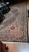 Overall view of red, blue and beige floral rug placed in room with furniture