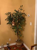 Full view of artificial tree in planter placed in corner showing height and scale.