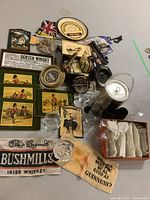 Overview of assorted Highland regiment place mats, Guinness and Bushmills towels, champagne flutes, ice bucket, coasters, and ashtrays arranged on a surface.