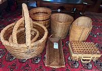 Overview of seven woven baskets of various shapes and sizes on a patterned red carpet.