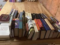 Books displayed on a table showing a variety of hard and soft cover books arranged in a row with titles partially visible.