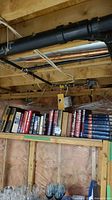 Books on a basement shelf showing a variety of hardcovers with visible titles and varied colors in a rustic setting.