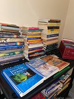 Books stacked on a black shelf including multiple titles by Tara Ward and Carlos Castaneda, and a red CD case.