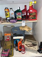 Shelf with various car care items including bottles of Turtle Wax, Supreme 800 oil, Grub-B-Gon insect remover, tire foam spray can, gloves, small blue basin and traction aids box, Valley hydraulic jack in carrying case in the background.